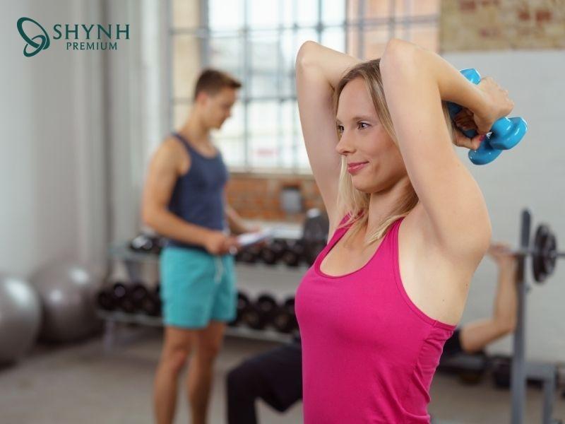 Duỗi tay sau đầu bằng nước hoặc tạ nhẹ giúp siết cơ tam đầu